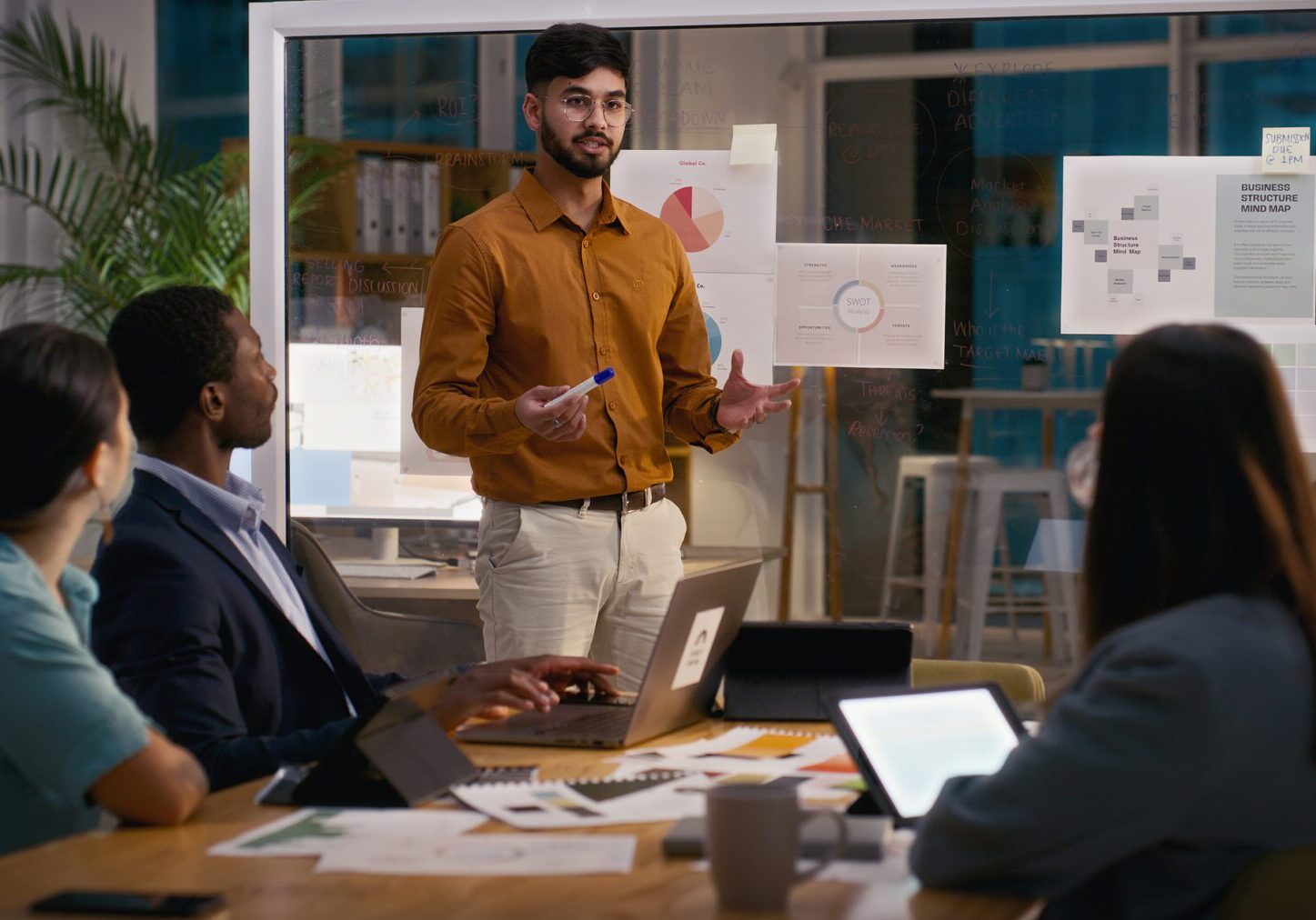 A man presenting to colleagues in a modern office meeting.