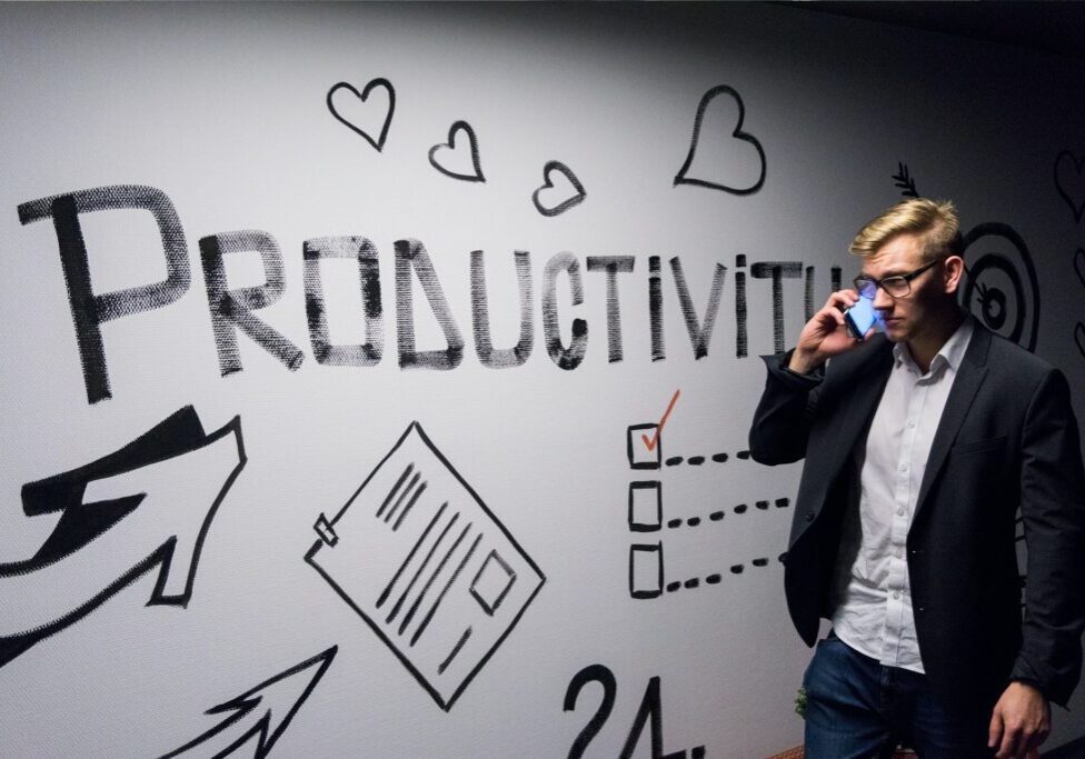 Man on phone near productivity-themed wall.