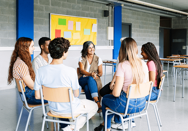 A group discussion session with people seated in a circle in a bright room.