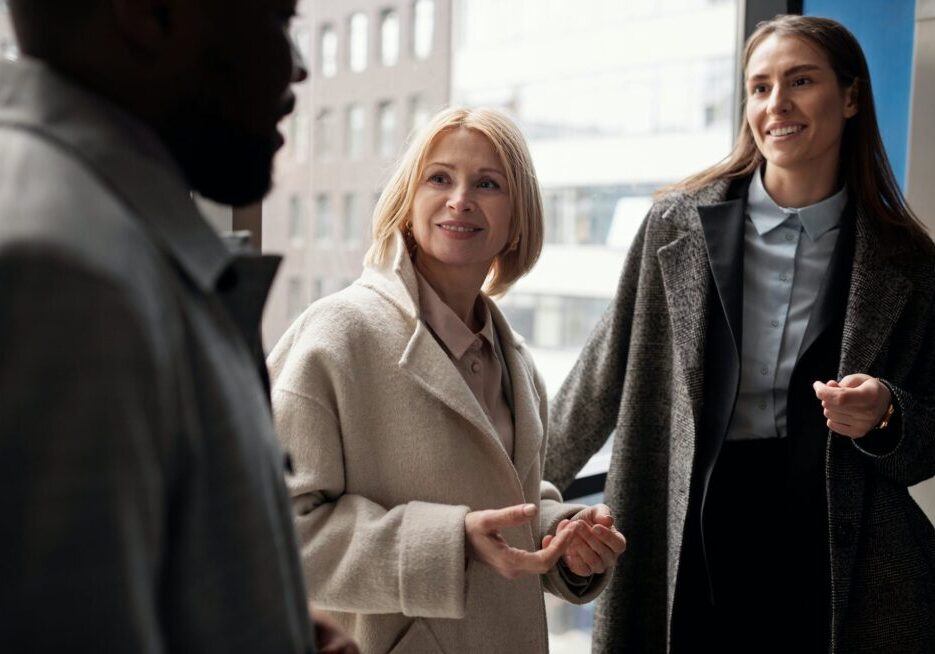 Three people talking by a window.