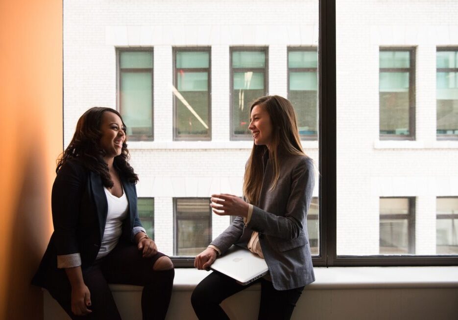 Two women talking by a window.