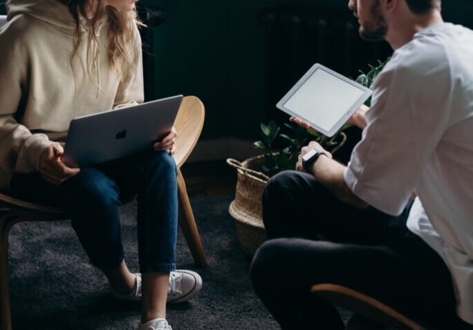 Two people discussing while holding tablets.