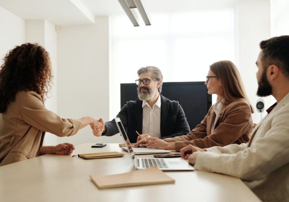 Business meeting handshake around conference table.