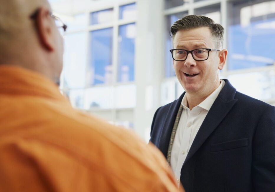 Two men talking in a bright office.