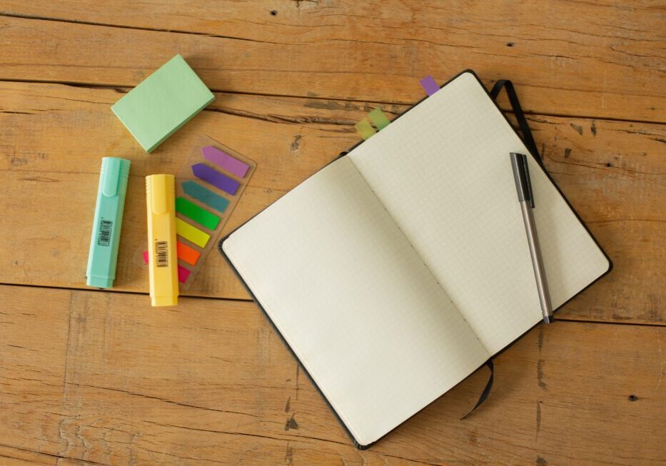 Open notebook with pen and colorful markers.