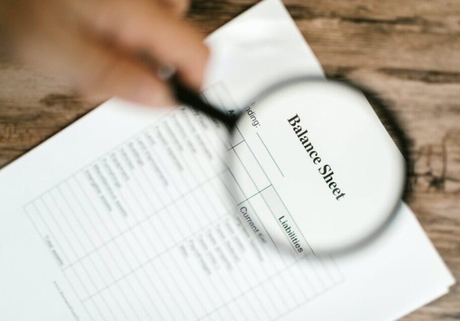 Magnifying glass over a balance sheet document.