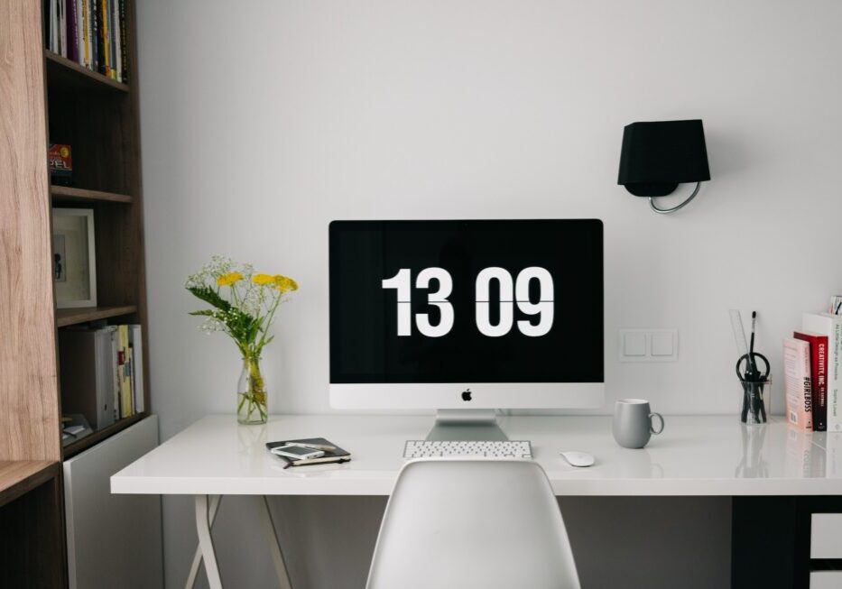Minimalist desk with computer and flowers.